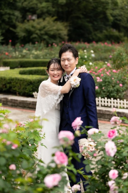 咲きそろうバラに囲まれて寄り添う新郎新婦。ピンクのバラ園で叶える東京の洋装ロケーションフォトウェディング