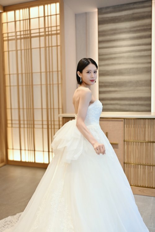 障子の前でビスチェのウェディングドレスの背中のリボンを見せて振り返る花嫁を縦位置でとらえた一枚。洋装前撮りで選べるウェディングドレスのバックスタイル