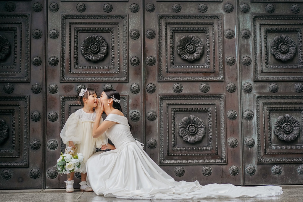 お母さんに内緒話をしている娘との可愛らしい結婚写真