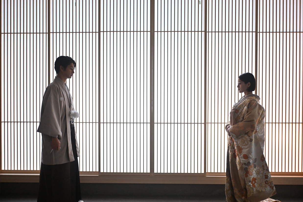 スタジオの素敵な和装背景の前に立つ新郎新婦