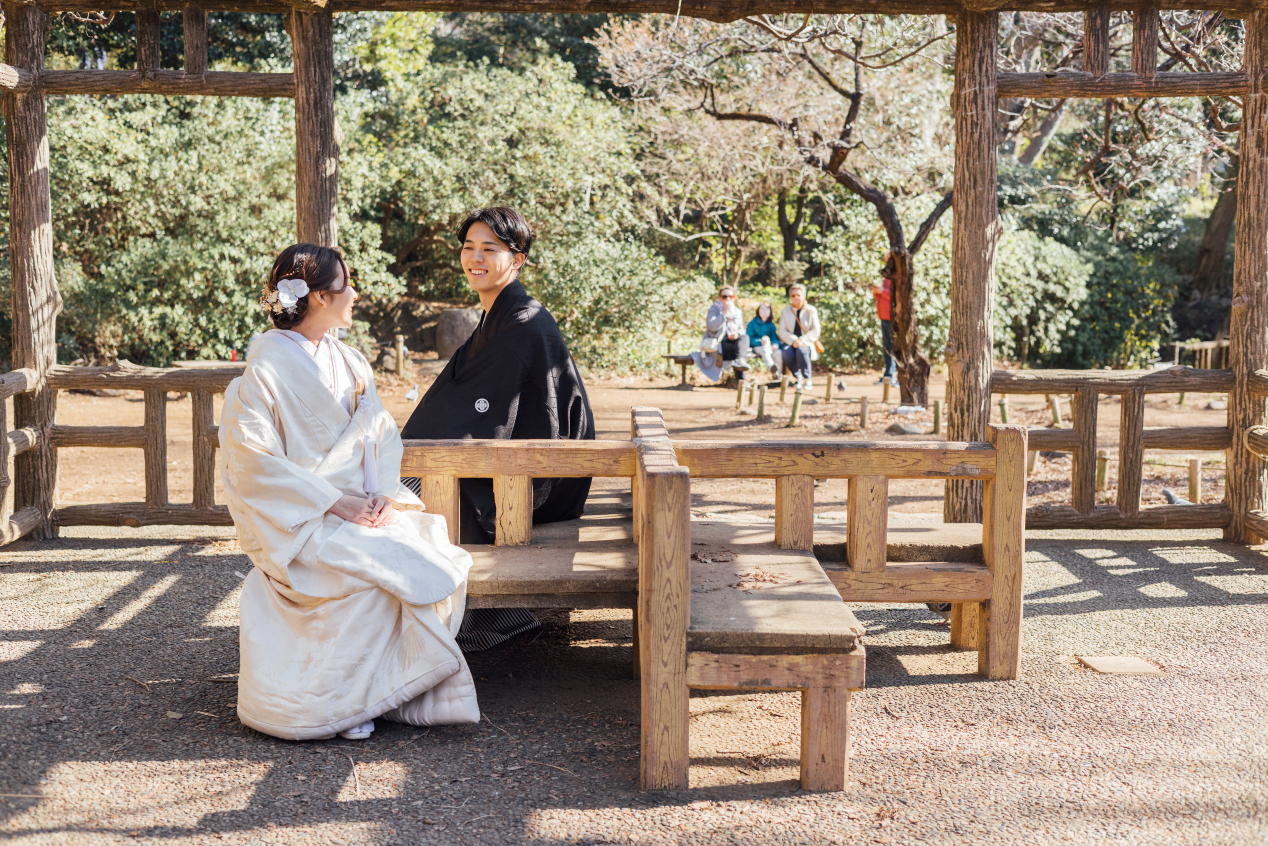 有栖川宮記念公園での和装前撮り撮影中、カメラマンのリードでリラックスした自然な表情で撮影に臨むカップルのイメージ