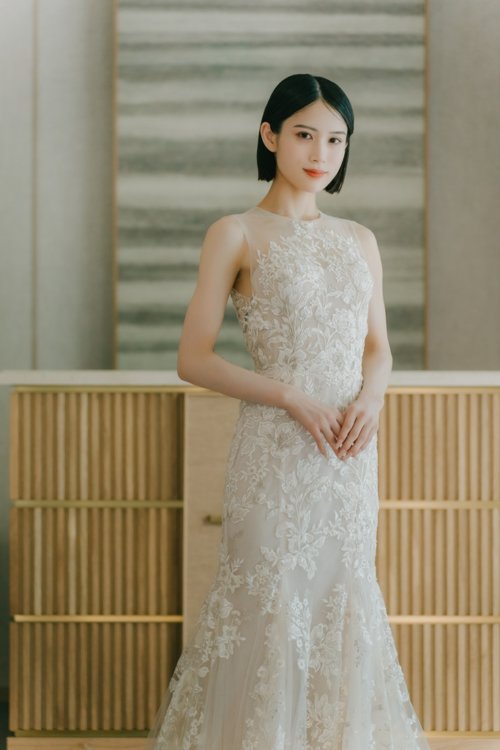 木の格子を背に手を重ねて正面を向くレースのマーメイドドレスの花嫁の全身カット。東京駅店のスタジオで撮る洋装前撮りの衣装写真