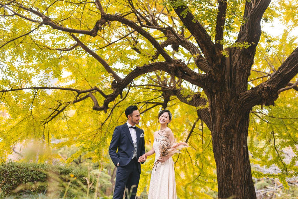 日比谷公園の紅葉シーズンでの洋装前撮り、赤・橙・黄に色づいた木々とウェディングドレスが映える都心の秋らしい一枚