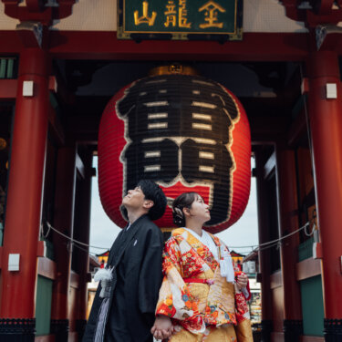 雷門の大提灯を並んで見上げる色打掛の花嫁と羽織袴の新郎。浅草ならではのロケーションを活かした和装フォトウェディングのポーズ
