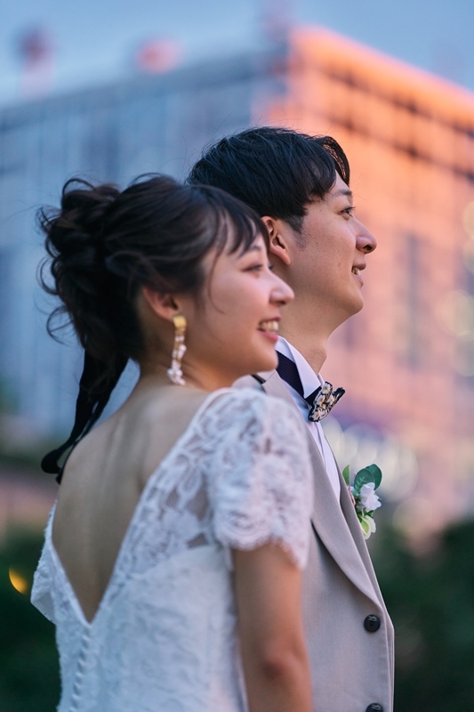 藍色に暮れてゆく空を背に、横顔を並べて同じ方向を見つめる新郎新婦のトワイライトフォトウェディング