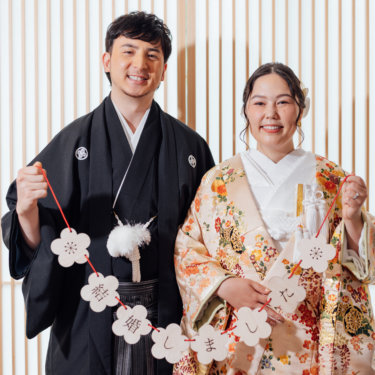 新郎の肩越しに微笑む白無垢の花嫁を縦位置でとらえた一枚。東京駅店のスタジオで撮る和装前撮り