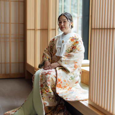 白い和傘とピンクの和傘を差して見つめ合う黒紋付袴の新郎と白無垢の花嫁。東京駅店のスタジオで撮る和装前撮り