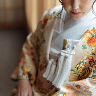 縦格子の障子の前で横を向く、花の髪飾りを付けた白無垢の花嫁の横顔。和装前撮りのブライダルポートレート
