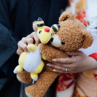 色打掛の花嫁と新郎が手にしたクマのぬいぐるみとキャラクターのぬいぐるみのアップ。ふたりらしさを添える和装前撮りの小物カット