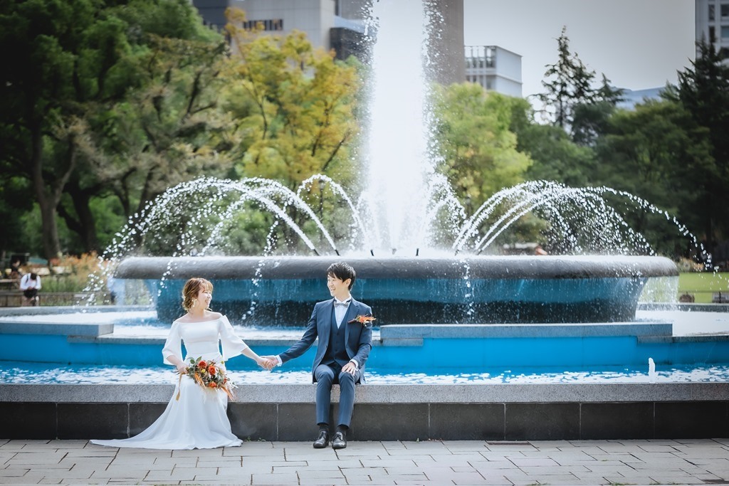 日比谷公園の噴水前での洋装前撮り、クラシカルな噴水とウェディングドレスが格調高く映える印象的な一枚