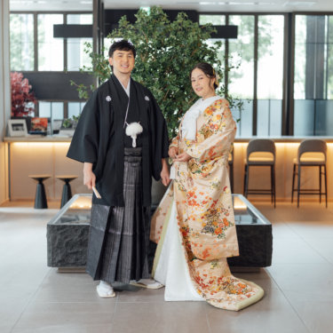 障子の前で赤い和傘を差して微笑む白無垢の花嫁。東京駅店のスタジオで撮る和装前撮りのブライダルポートレート