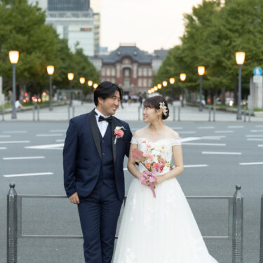 いちょう並木の行幸通りの奥に東京駅が見える場所で、ブーケを持つ花嫁と見つめ合うタキシードの新郎。丸の内の洋装ロケーションフォト