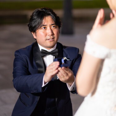 指輪のケースを差し出してひざまずく新郎と、口元に手を当てて驚く花嫁。プロポーズを再現した前撮りの一枚