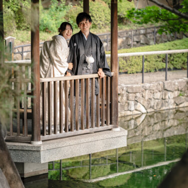 池にせり出した木造の東屋で寄り添う白無垢と紋付袴の新郎新婦。日本庭園の水辺で撮る和装前撮り