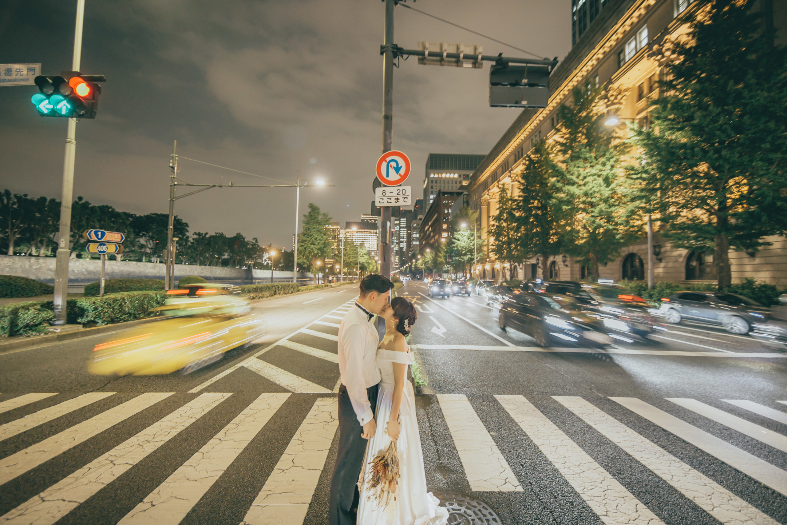 馬場先門の交差点で、行き交う車の光跡に包まれてキスを交わす新郎新婦の東京駅ナイトフォト