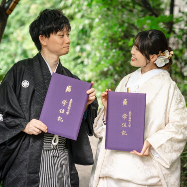 紫色の学位記ファイルを胸に見つめ合う紋付袴の新郎と白無垢の花嫁。思い出の品を持ち込んだ目白庭園の和装前撮り