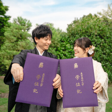 青空の下で学位記のファイルを掲げて笑う新郎新婦。ふたりの思い出のアイテムを取り入れた和装フォトウェディング