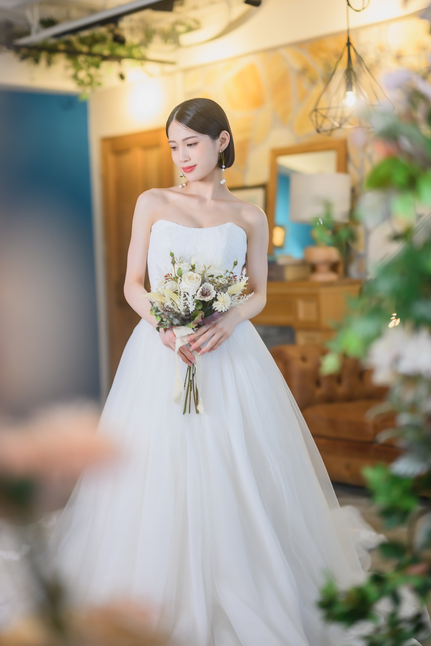 ブルーの壁とアートが映えるスタジオで、チュールのAラインドレスにブーケを持って佇む花嫁のフォトウェディング（東京駅店）