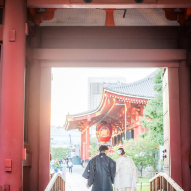二天門の内側から境内へ歩いていく紋付袴と白無垢のおふたりの後ろ姿。浅草寺で撮る和装ロケーションフォト