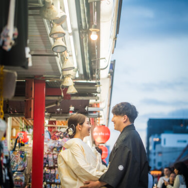 夕暮れの仲見世通りの店先で、白無垢の花嫁を抱き寄せて見つめ合う紋付袴の新郎の和装フォトウェディング