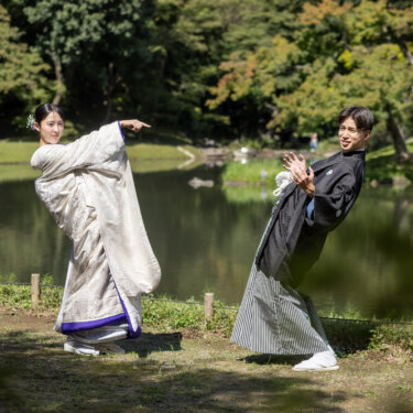 池のほとりで後ろ向きに身をそらし、顔だけこちらに向ける白無垢の花嫁と紋付袴の新郎。遊び心のある和装前撮り