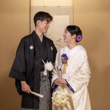 床の間の前で白いブーケを持ち、笑顔で見つめ合う紋付袴の新郎と白無垢の花嫁。小石川後楽園で撮る和装前撮り