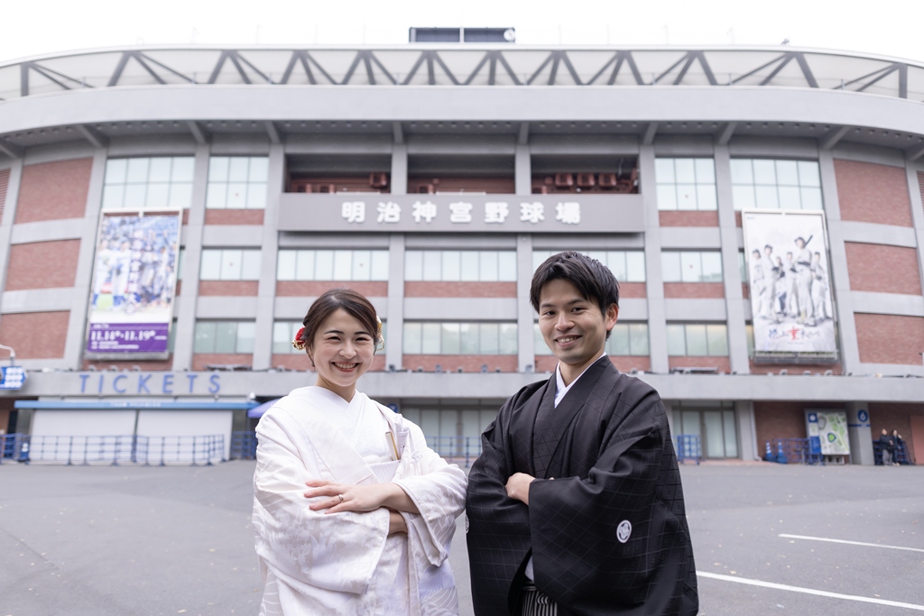 神宮球場を背景に並んで立つ白無垢の花嫁と紋付袴の新郎。思い出の場所で撮る和装前撮り