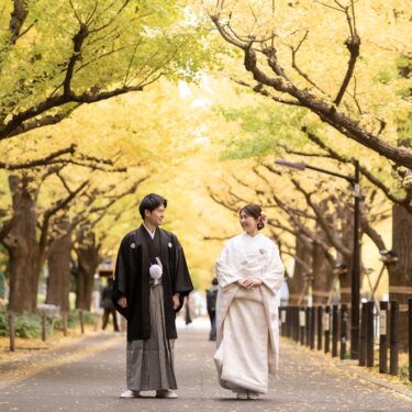 黄金色に色づいた外苑いちょう並木の歩道を、並んで歩く白無垢の花嫁と紋付袴の新郎。秋の和装前撮り